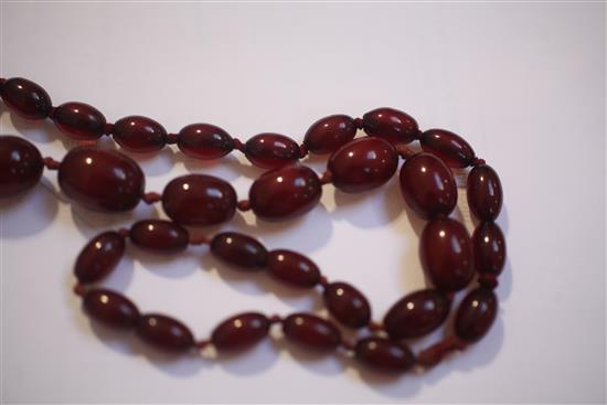 Two single strand red simulated amber bead necklaces, largest 158cm.